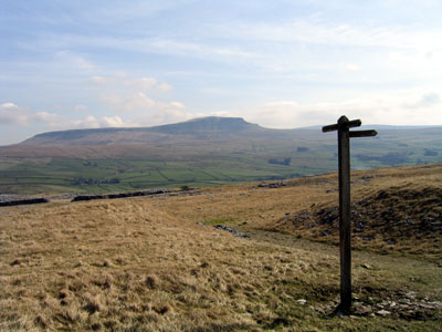Path leading up to the signpost from the gap in the wall