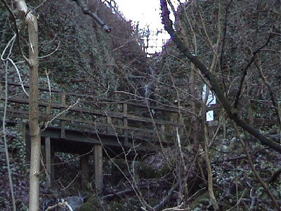 Wooden footbridge with waterfall behind