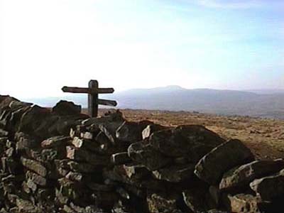 Footpath sign on the summit with Ingleborough visible on the horizon